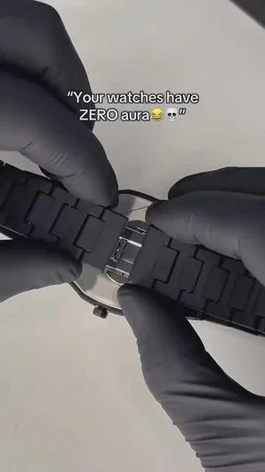 Person in black gloves adjusting black watch strap with metal clasp on a silver wristwatch.