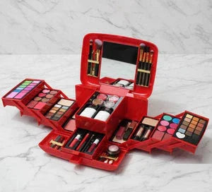 Red makeup organizer box open with multiple cosmetic palettes, brushes, and a mirror